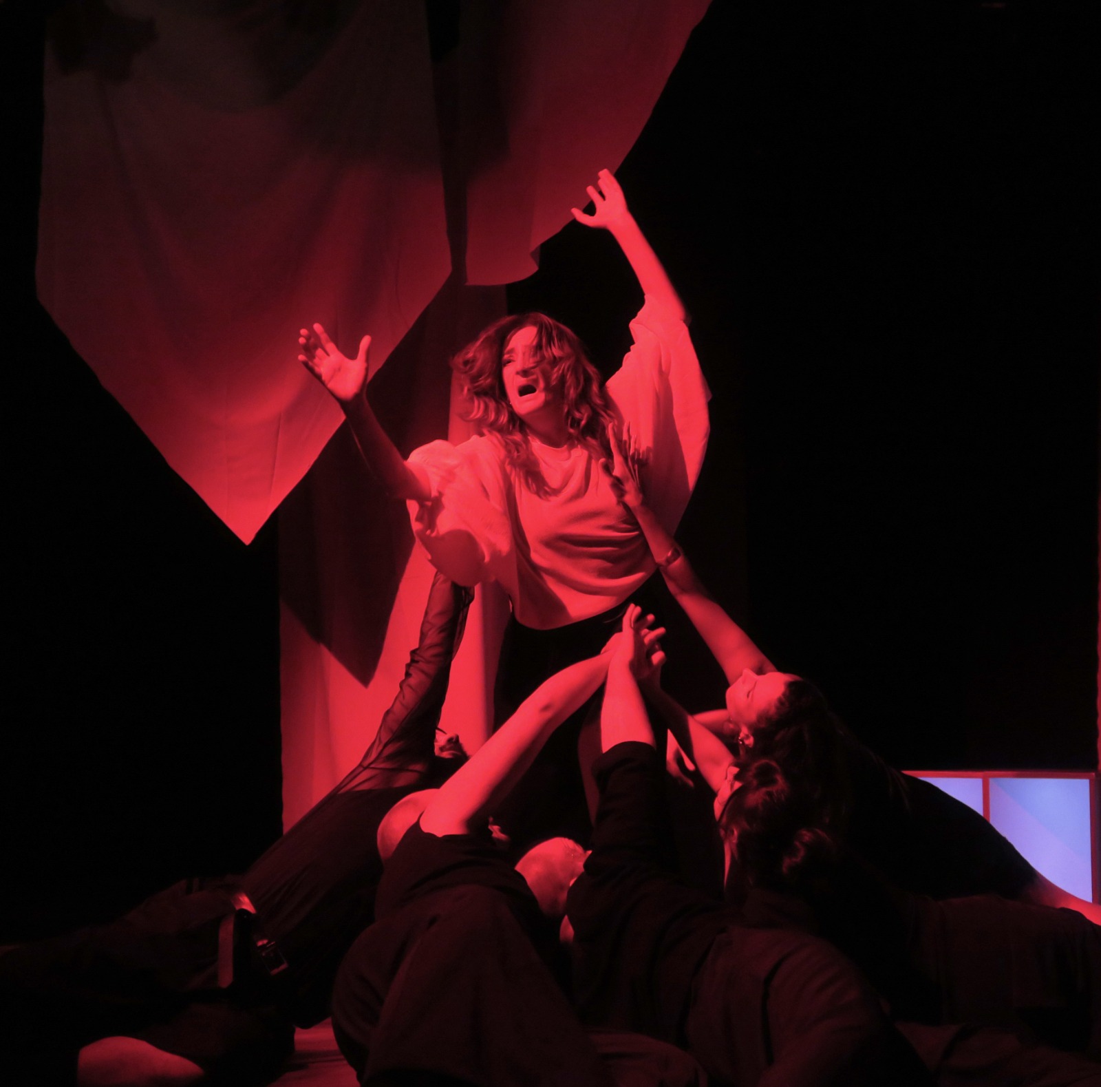 Intérpretes de Fila Cero en una escena coral bajo iluminación roja